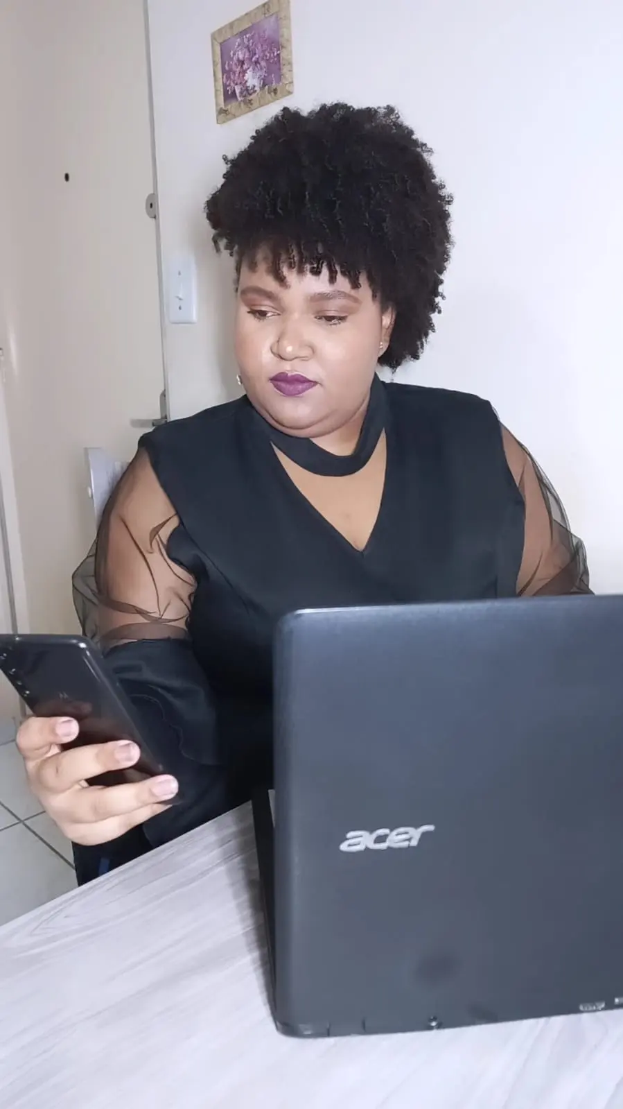 Iris Karoline ao celular, com o notebook ao lado