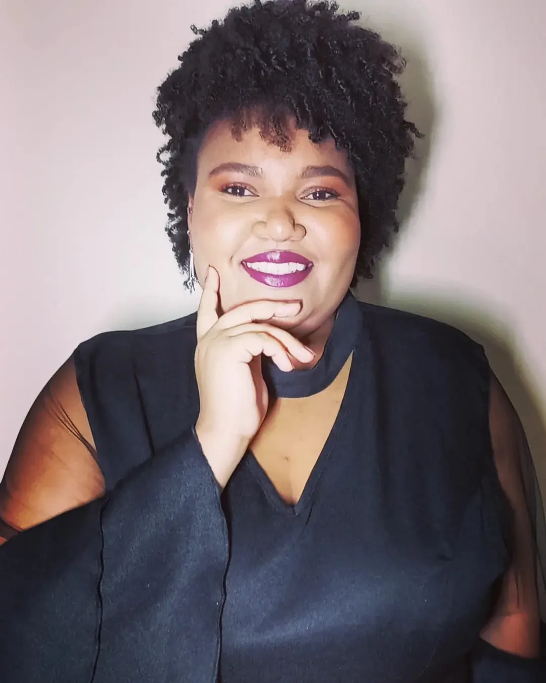 Iris Karoline sorrindo, com a mão no queixo